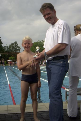 Der achtjährige Fabian Scheller nimmt beim 17. Heinz-Lenfert-Pokalschwimmen von ASG-Chef Heinrich Steinhoff den Ehrenpokal entgegen.